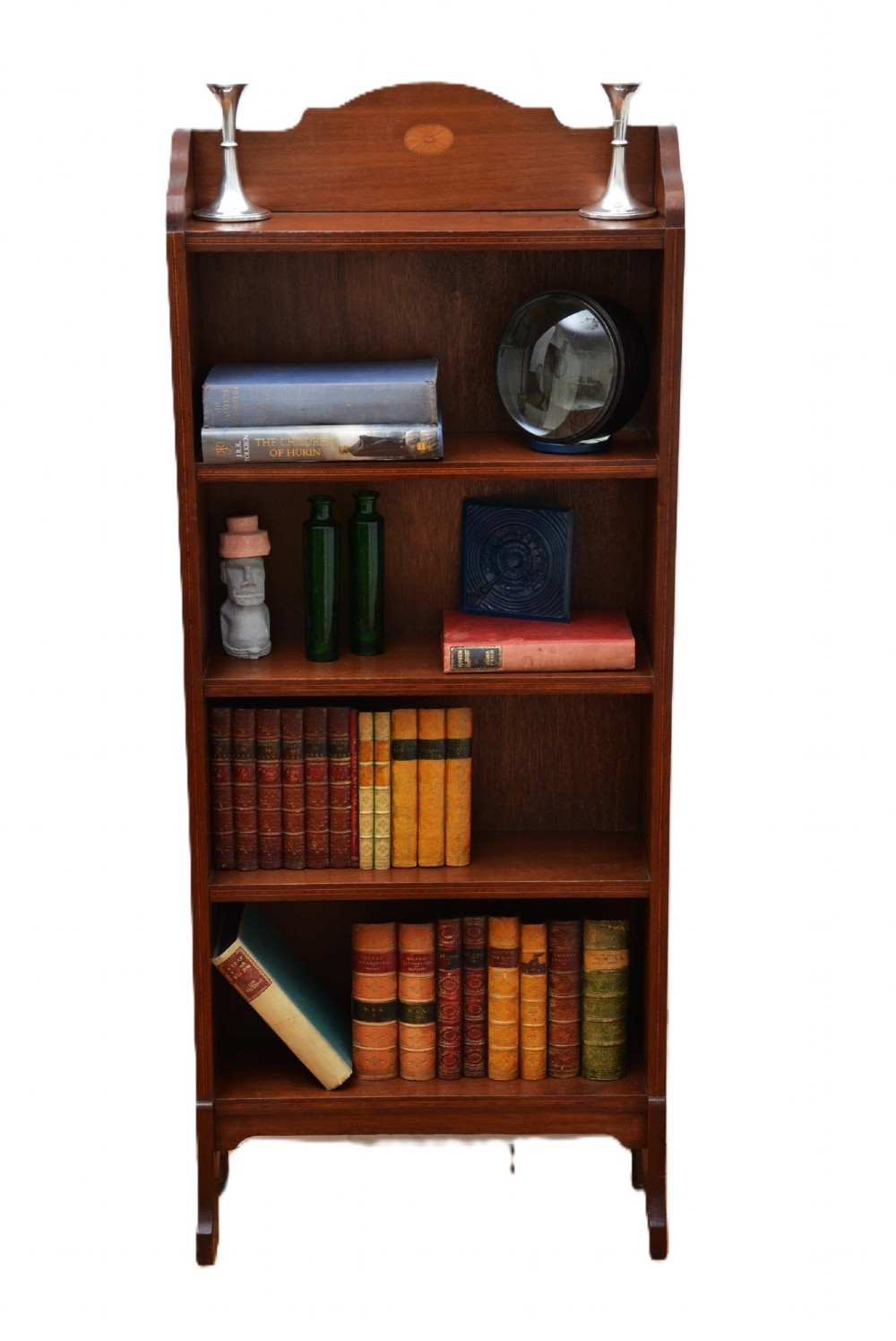 A slim Edwardian mahogany open bookcase featuring four shelves, an inlaid oval motif on the shaped gallery top, and bracket feet.