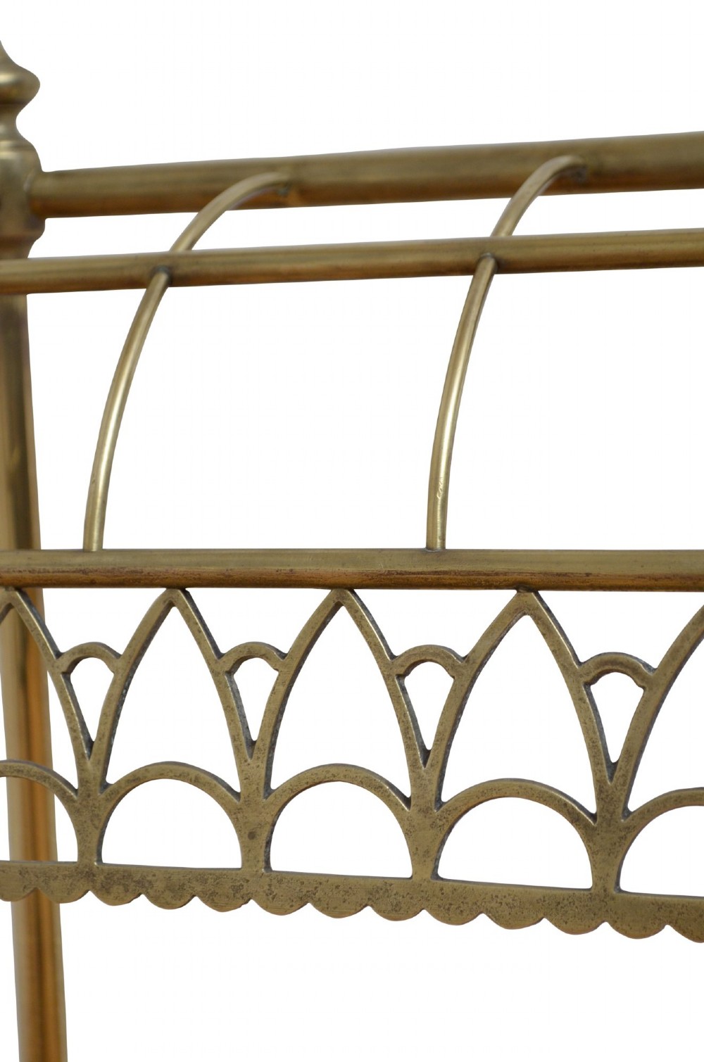 A Victorian tubular brass umbrella stand featuring a curved upper section with internal divisions, finial caps, a arched fretwork apron, and a black cast iron drip tray base. View VI
