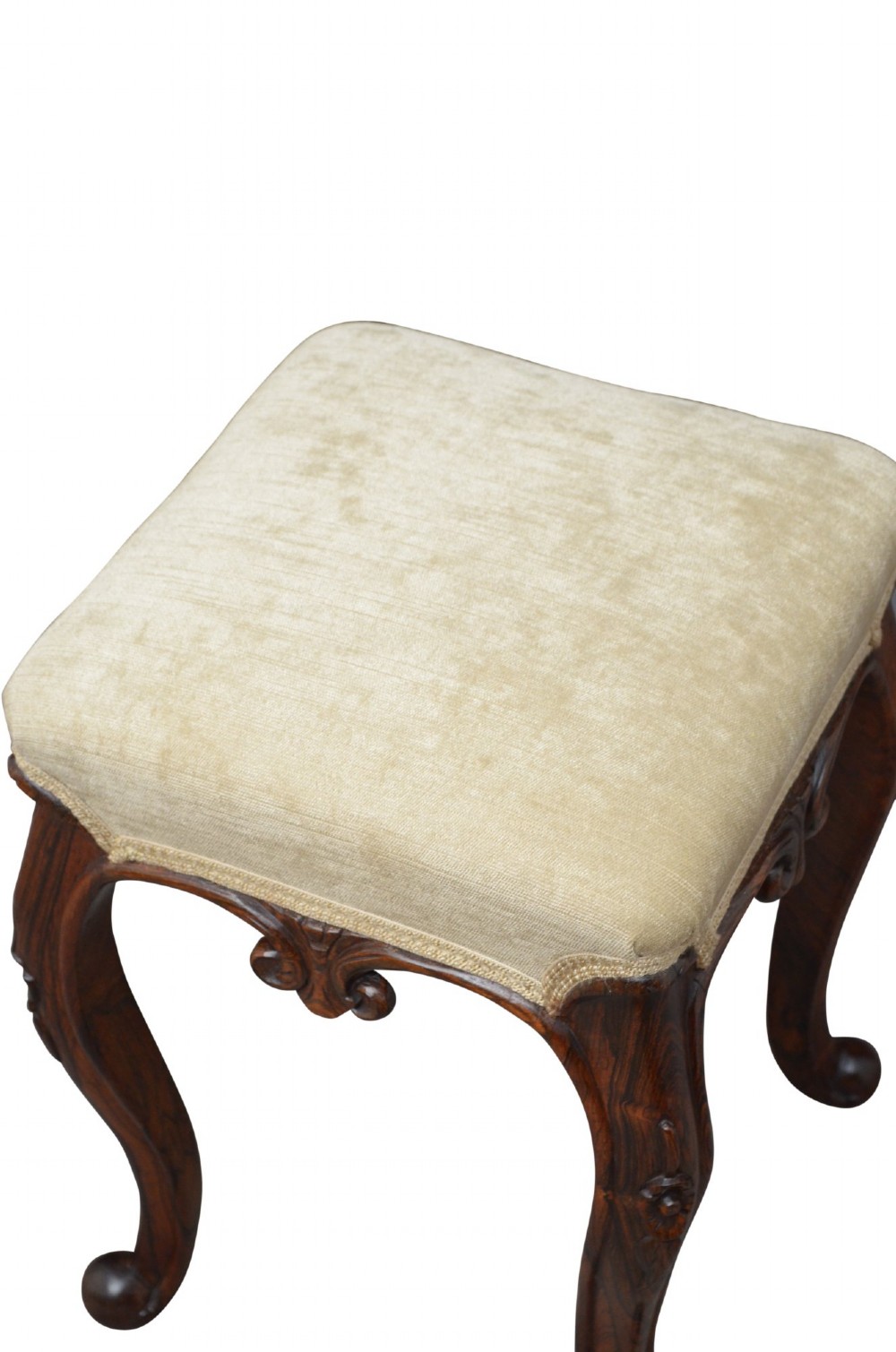 An antique carved dark rosewood stool featuring cabriole legs and a neutral upholstered padded seat. View IV