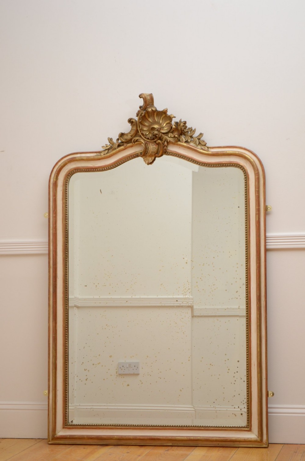 An arched French Chateau style wall mirror featuring a gilded wooden frame topped with a decorative carved shell crest. View II