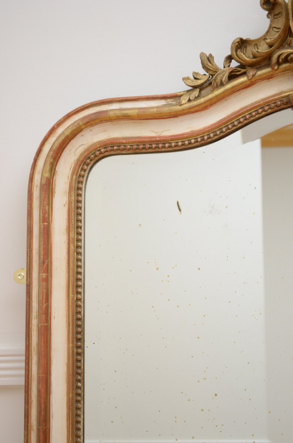 An arched French Chateau style wall mirror featuring a gilded wooden frame topped with a decorative carved shell crest. View IV