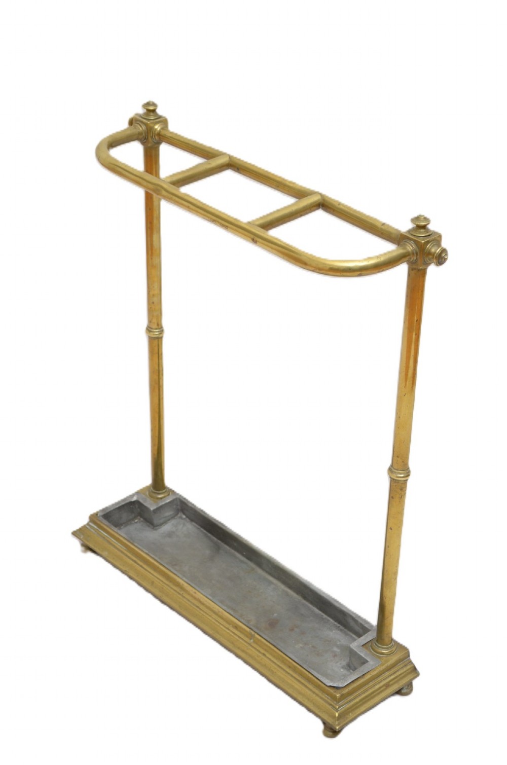 A Victorian brass umbrella stand featuring three divided upper slots, vertical supports, small bun feet, and a metal drip tray.