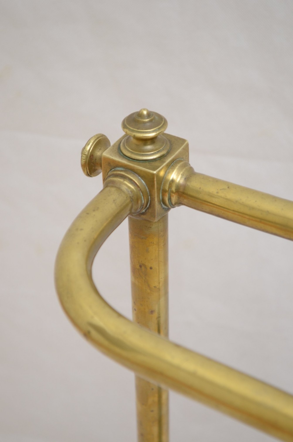 A Victorian brass umbrella stand featuring three divided upper slots, vertical supports, small bun feet, and a metal drip tray. View IV