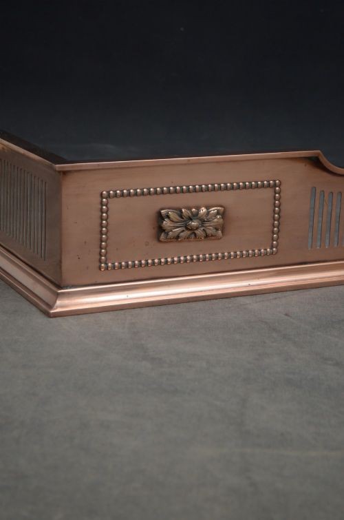 An antique Victorian copper fireplace fender featuring pierced vertical slots and side panels embellished with raised floral paterae and beaded edging. View VII