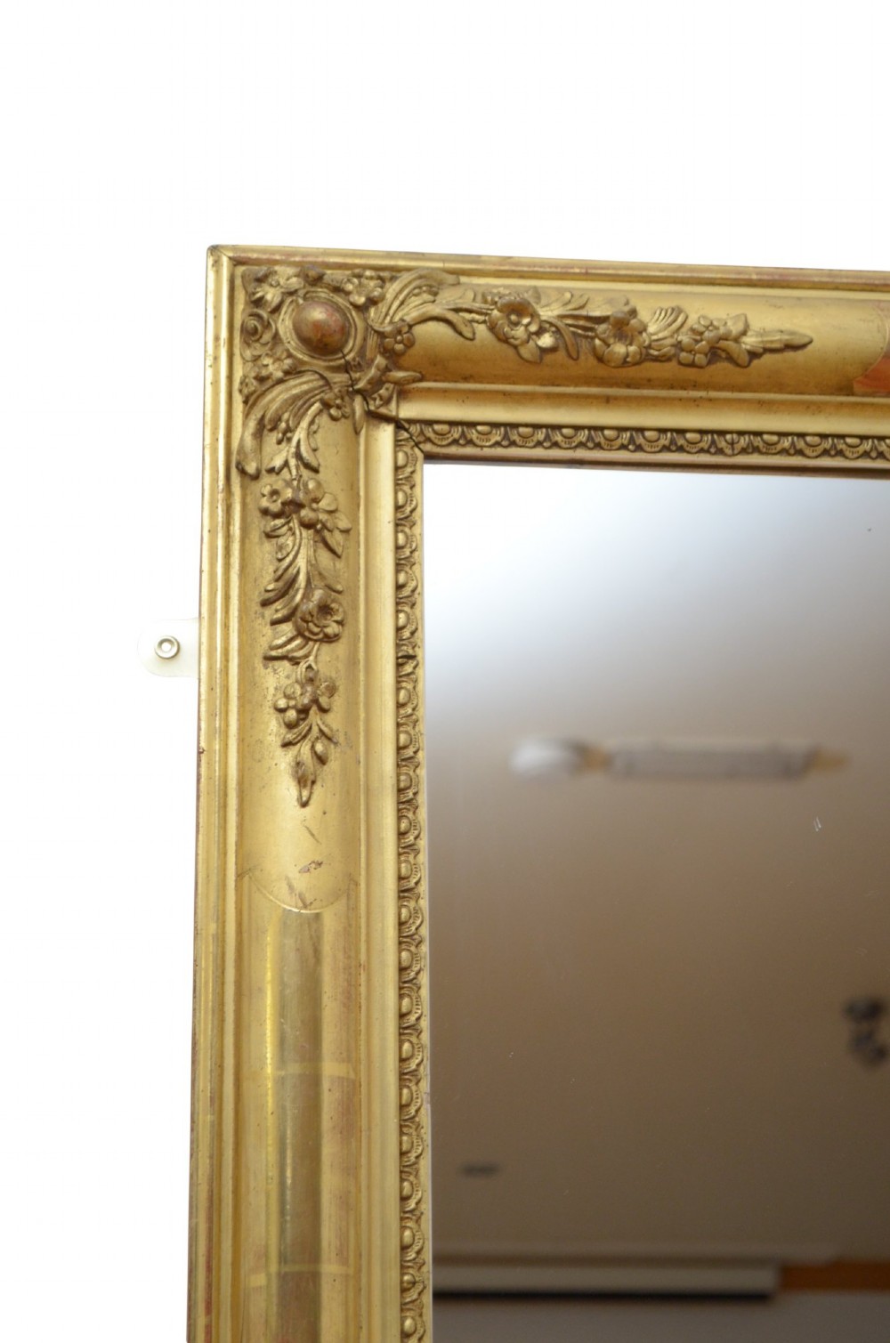 A large rectangular antique giltwood wall mirror with carved floral corner details and a beaded inner border. View II