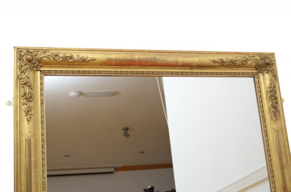 A large rectangular antique giltwood wall mirror with carved floral corner details and a beaded inner border. View IV