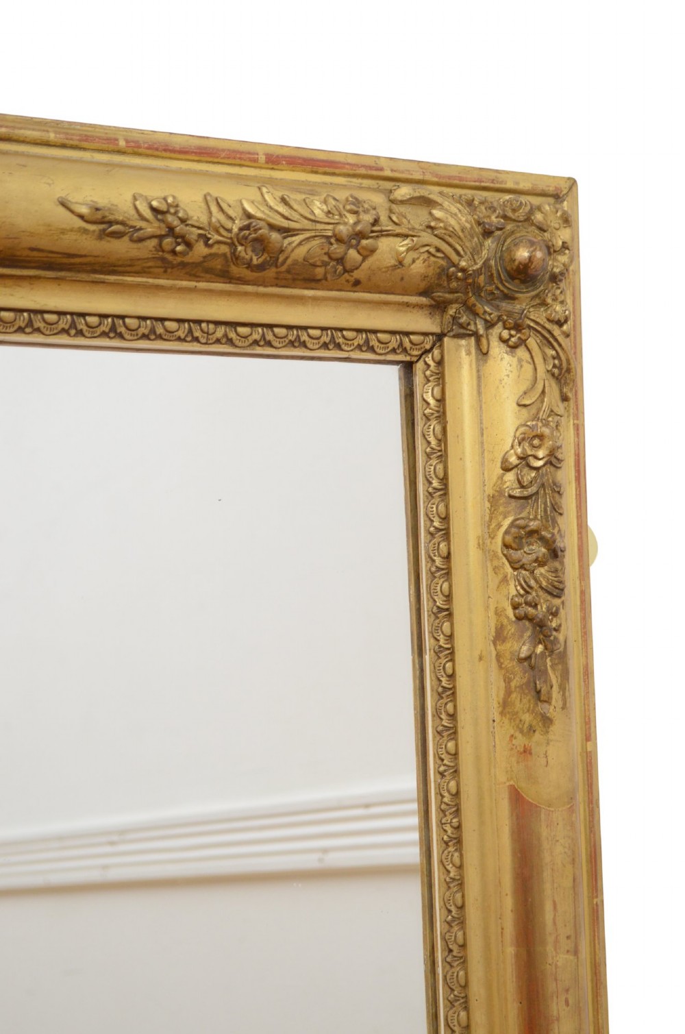 A large rectangular antique giltwood wall mirror with carved floral corner details and a beaded inner border. View V