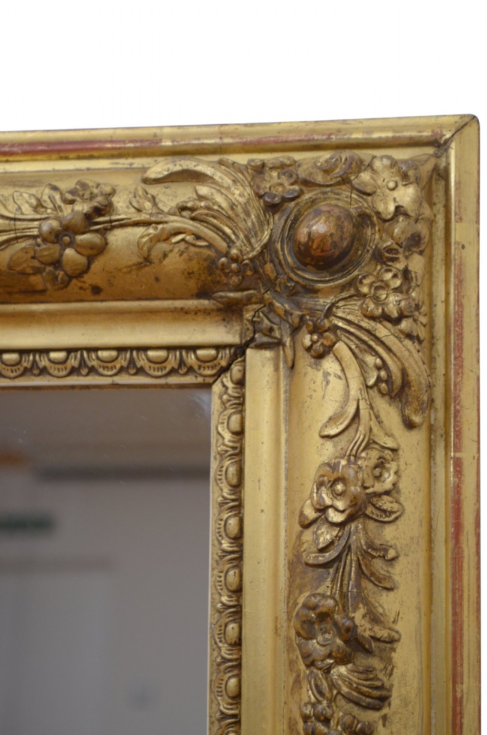 A large rectangular antique giltwood wall mirror with carved floral corner details and a beaded inner border. View VI