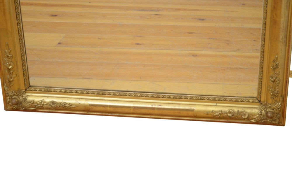 A large rectangular antique giltwood wall mirror with carved floral corner details and a beaded inner border. View XI