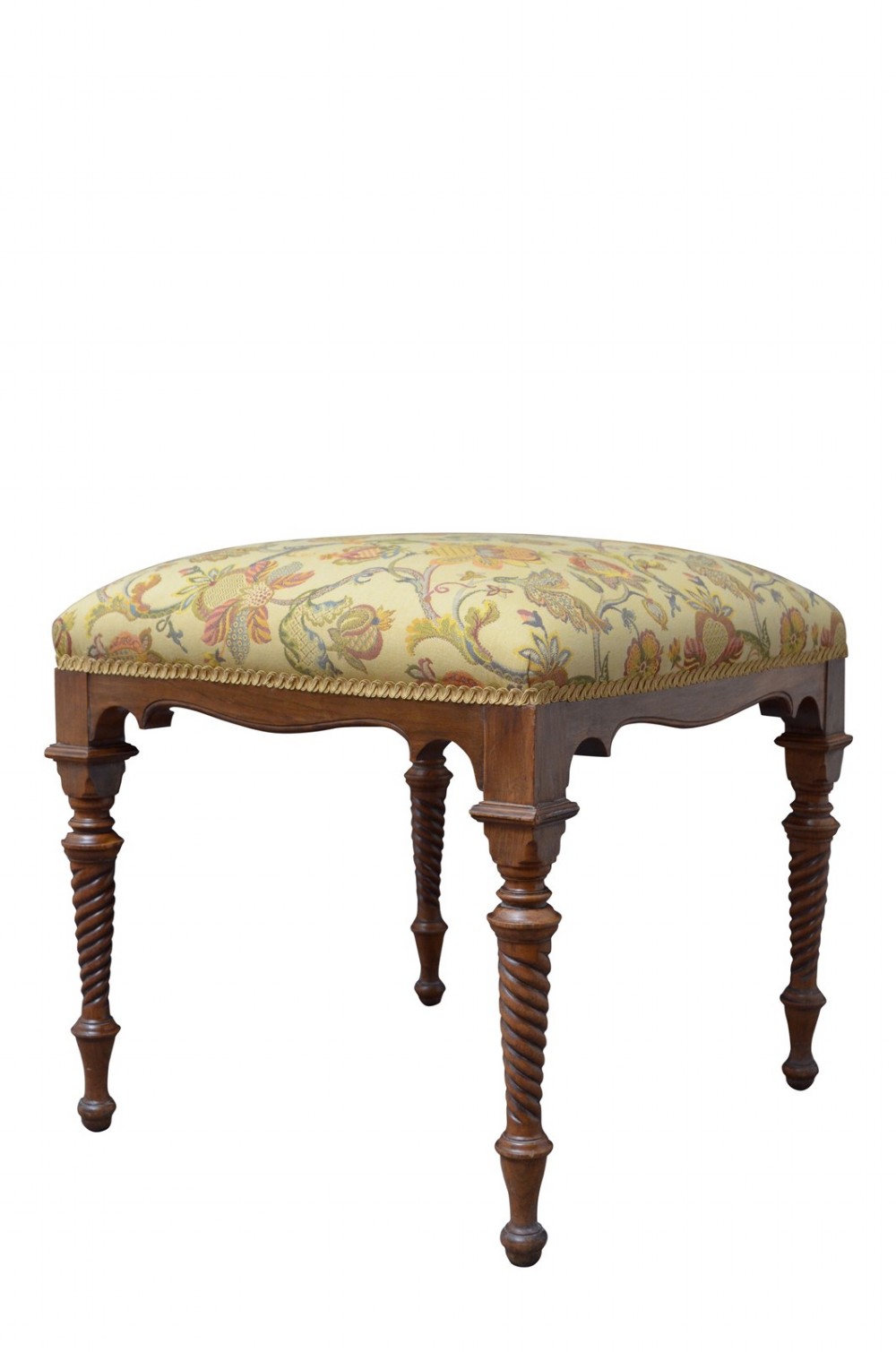 A walnut dressing table stool with turned barley twist legs and a padded seat upholstered in yellow floral patterned fabric.