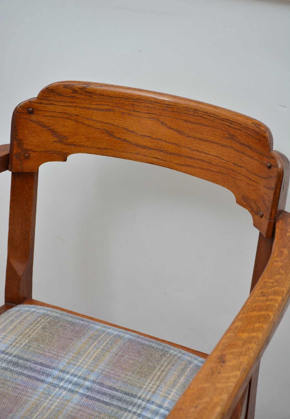 An oak Arts and Crafts desk chair featuring straight armrests, a rectangular backrest, and a blue and grey plaid upholstered seat. View III
