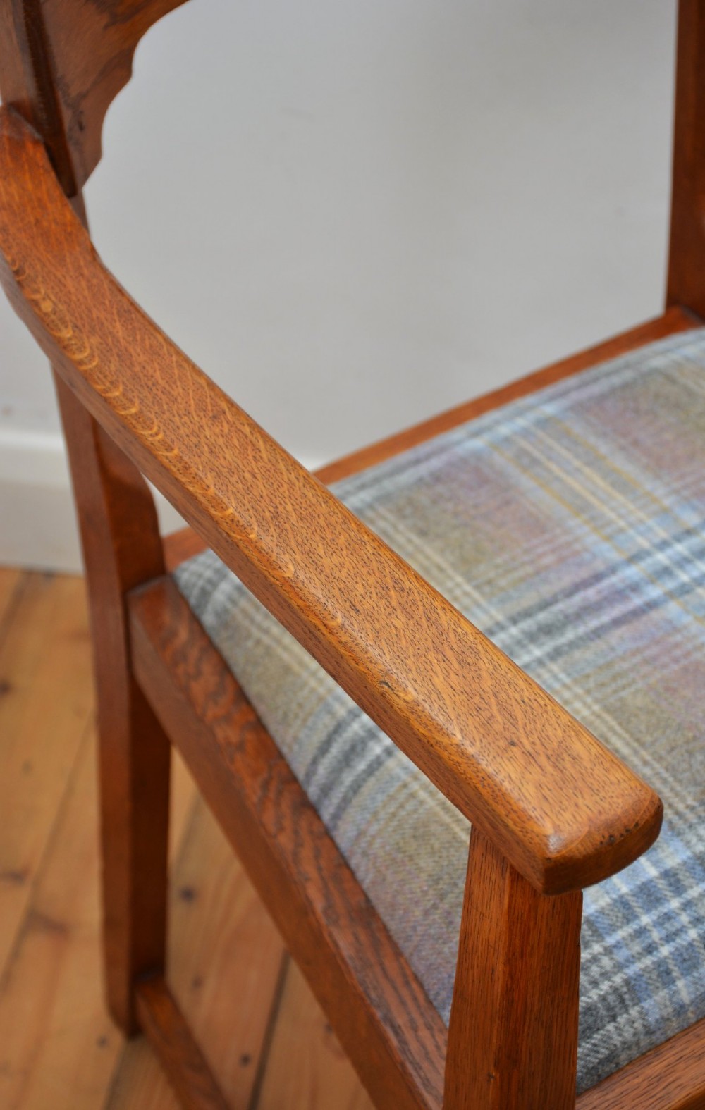 An oak Arts and Crafts desk chair featuring straight armrests, a rectangular backrest, and a blue and grey plaid upholstered seat. View V