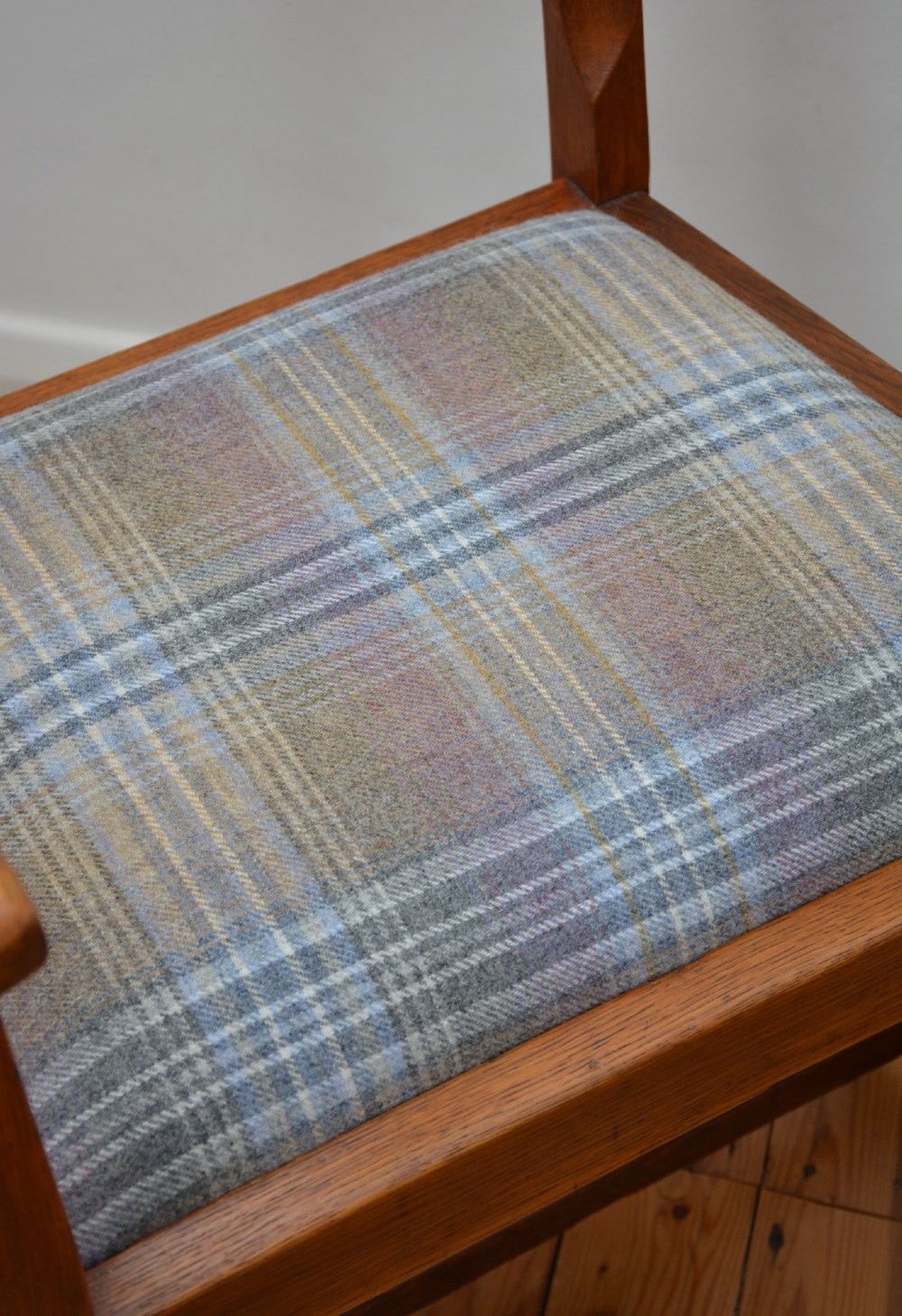 An oak Arts and Crafts desk chair featuring straight armrests, a rectangular backrest, and a blue and grey plaid upholstered seat. View VI