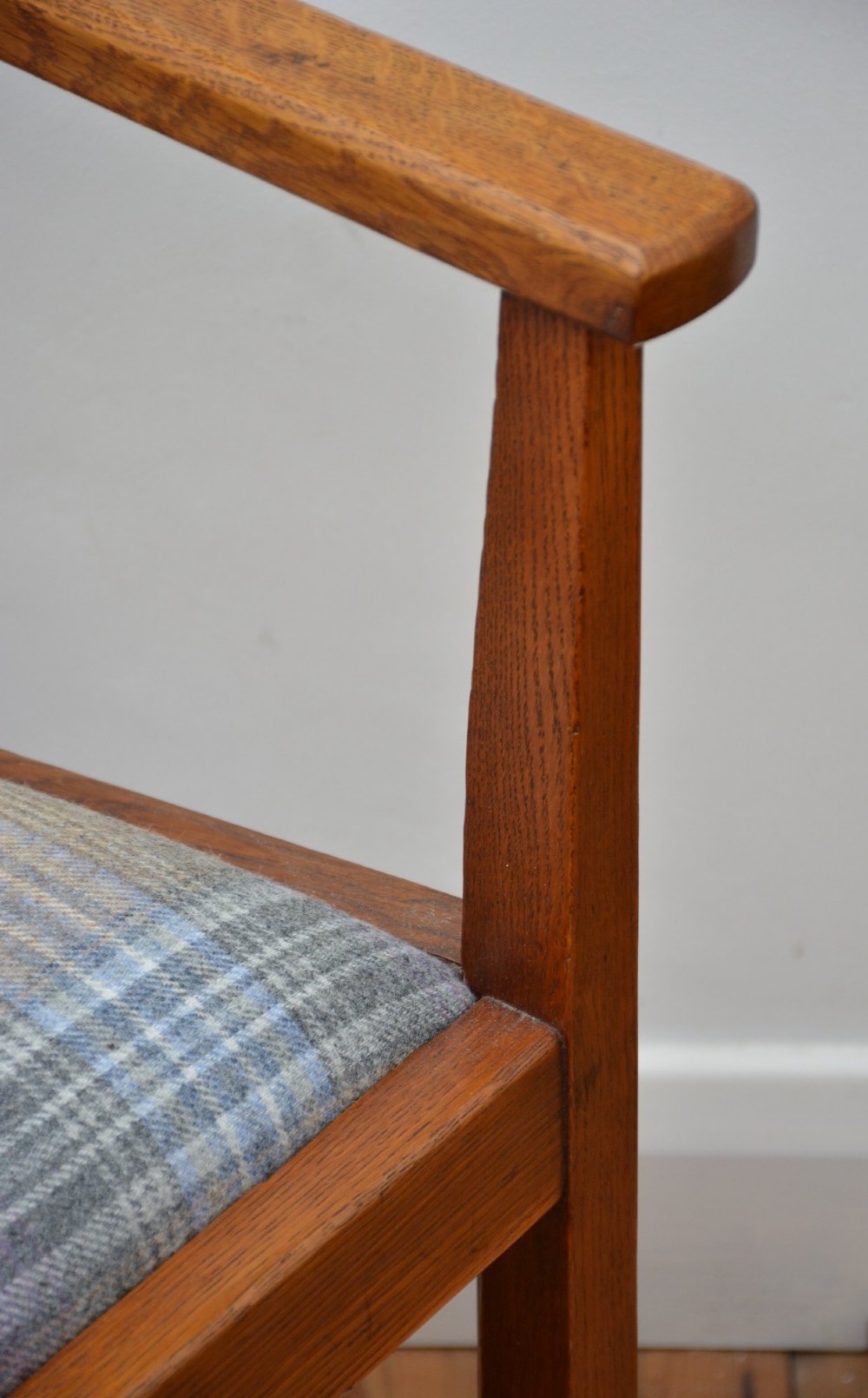 An oak Arts and Crafts desk chair featuring straight armrests, a rectangular backrest, and a blue and grey plaid upholstered seat. View IX
