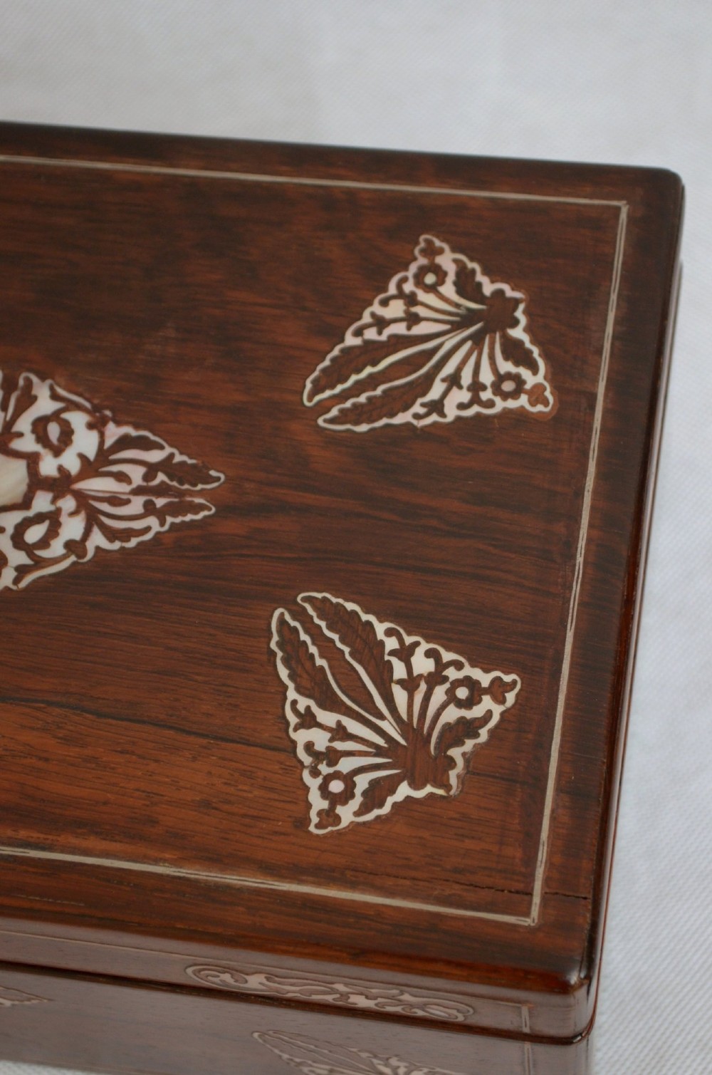 A rectangular dark rosewood jewellery box featuring brass foliate inlays and a central brass keyhole escutcheon. View VII