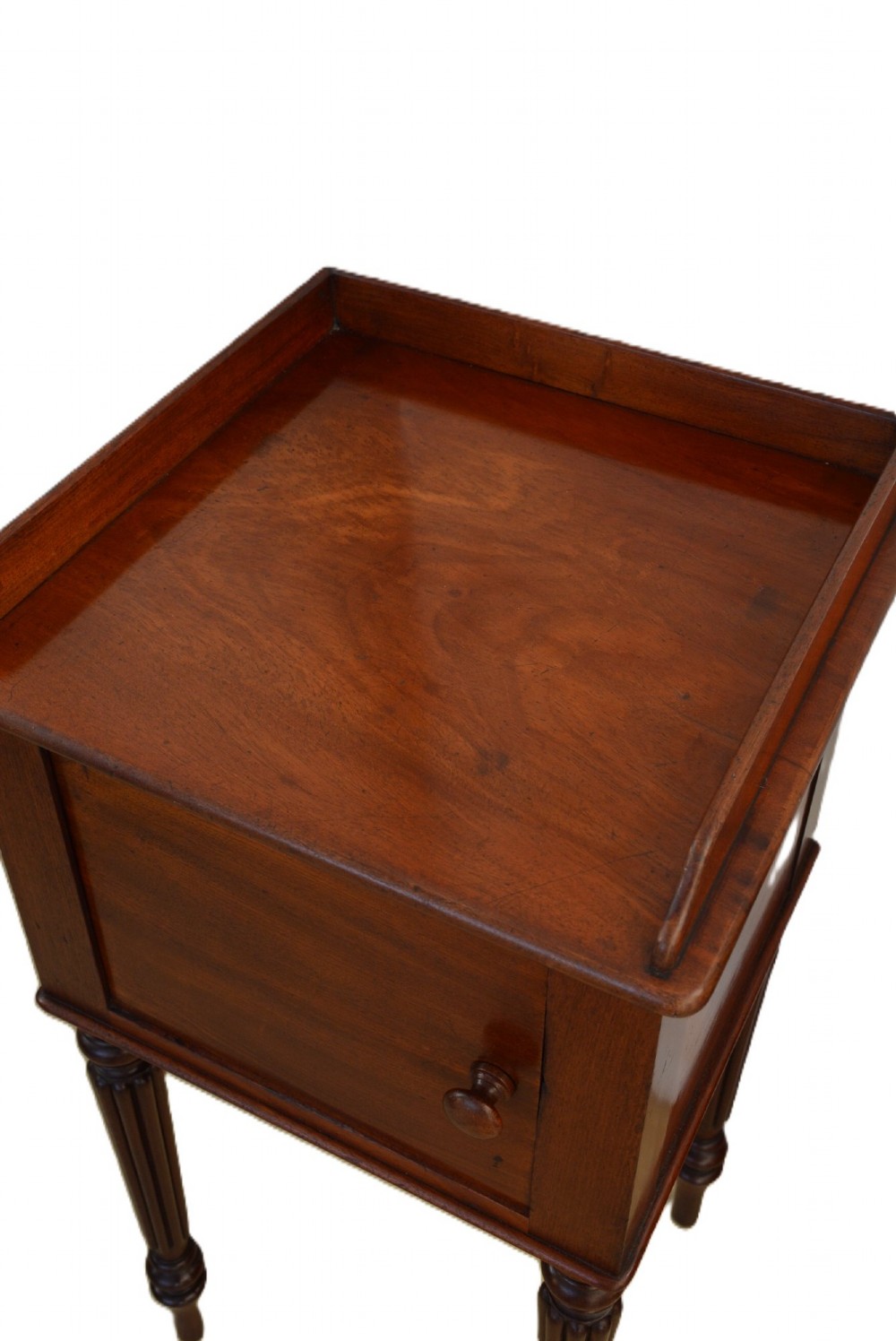A dark mahogany bedside cabinet featuring a three-sided gallery top, a single door with a turned wooden knob, and four slender reeded legs. View IX