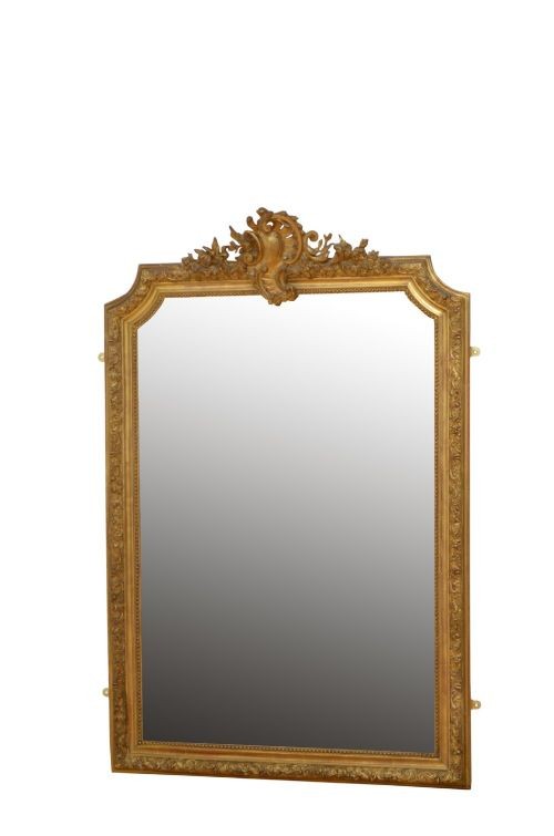A tall antique giltwood wall mirror featuring an ornate carved floral cresting at the top, decorative foliate moulding along the frame, and original glass.