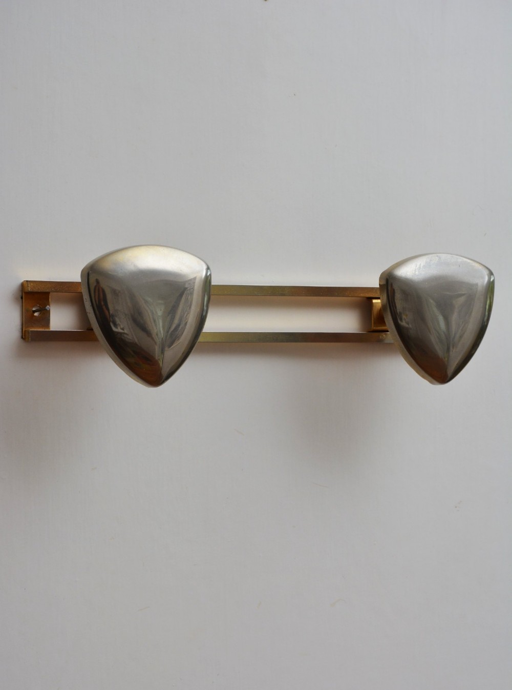 A set of two silver shield-shaped coat hooks mounted on a horizontal gold-toned metal wall bar. View III