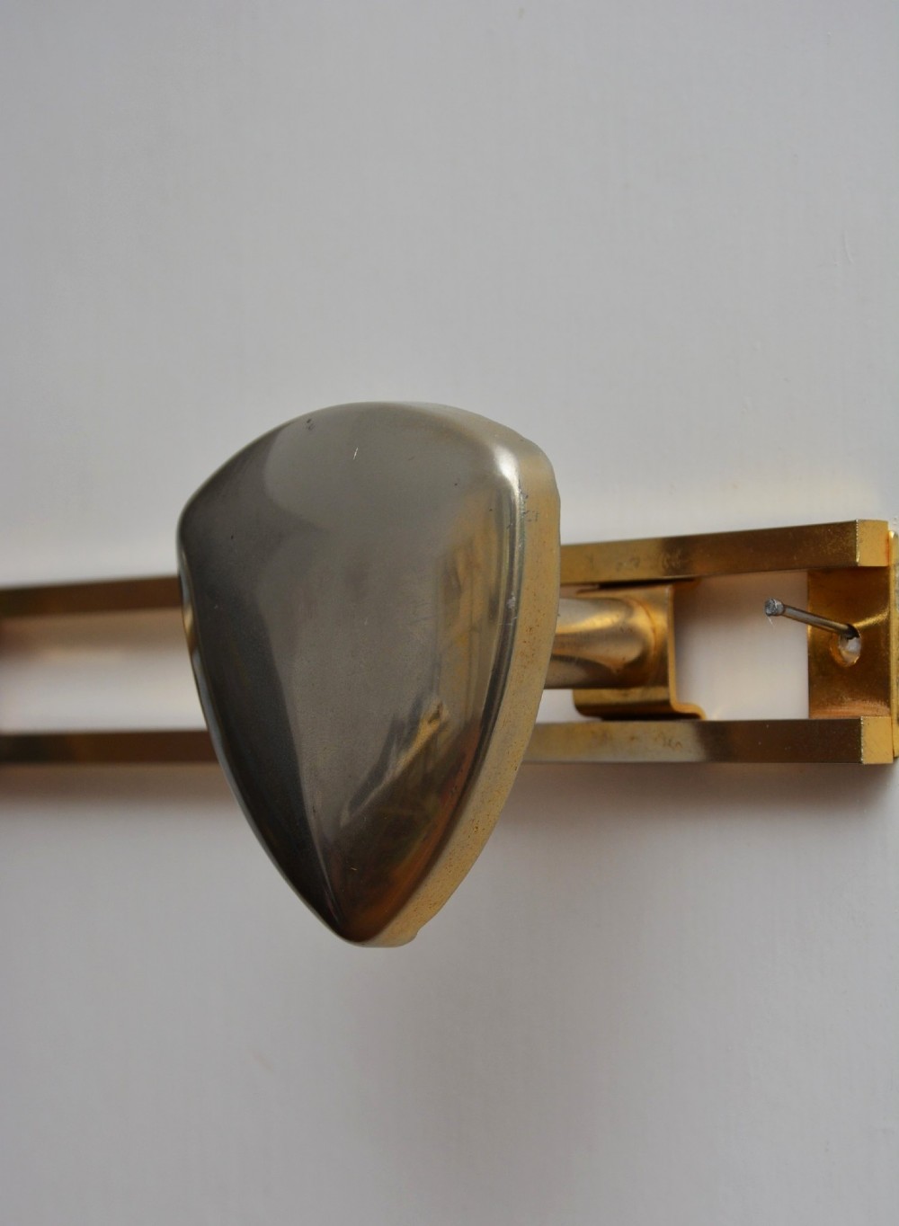A set of two silver shield-shaped coat hooks mounted on a horizontal gold-toned metal wall bar. View IV