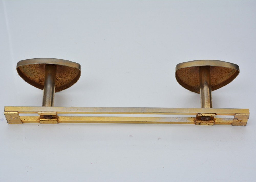 A set of two silver shield-shaped coat hooks mounted on a horizontal gold-toned metal wall bar. View VIII