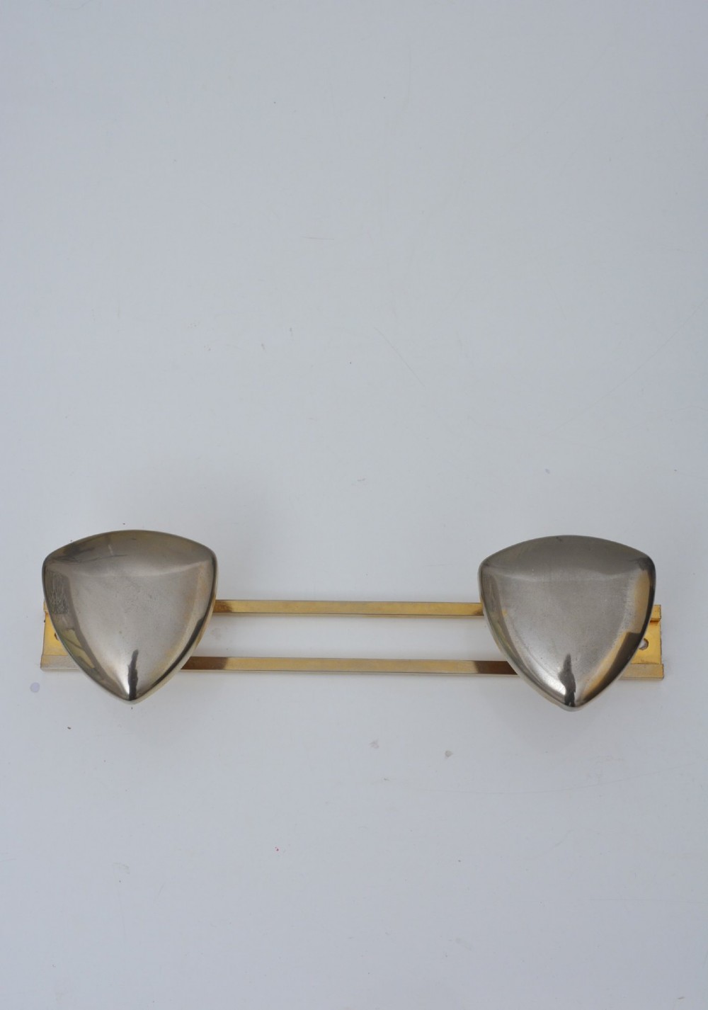 A set of two silver shield-shaped coat hooks mounted on a horizontal gold-toned metal wall bar. View X