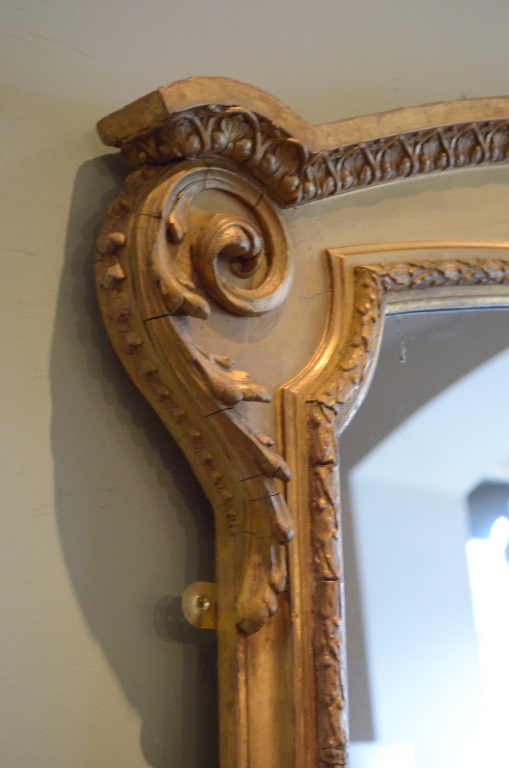 A large arched giltwood overmantel mirror featuring decorative floral moulding and side scroll details. View IV