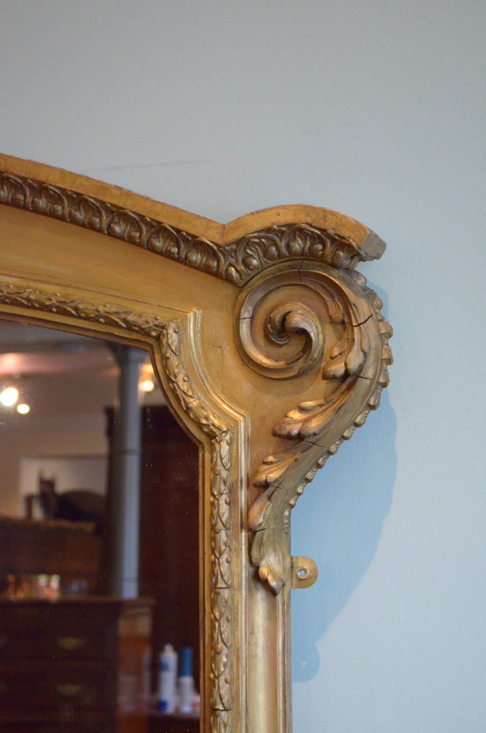 A large arched giltwood overmantel mirror featuring decorative floral moulding and side scroll details. View VII
