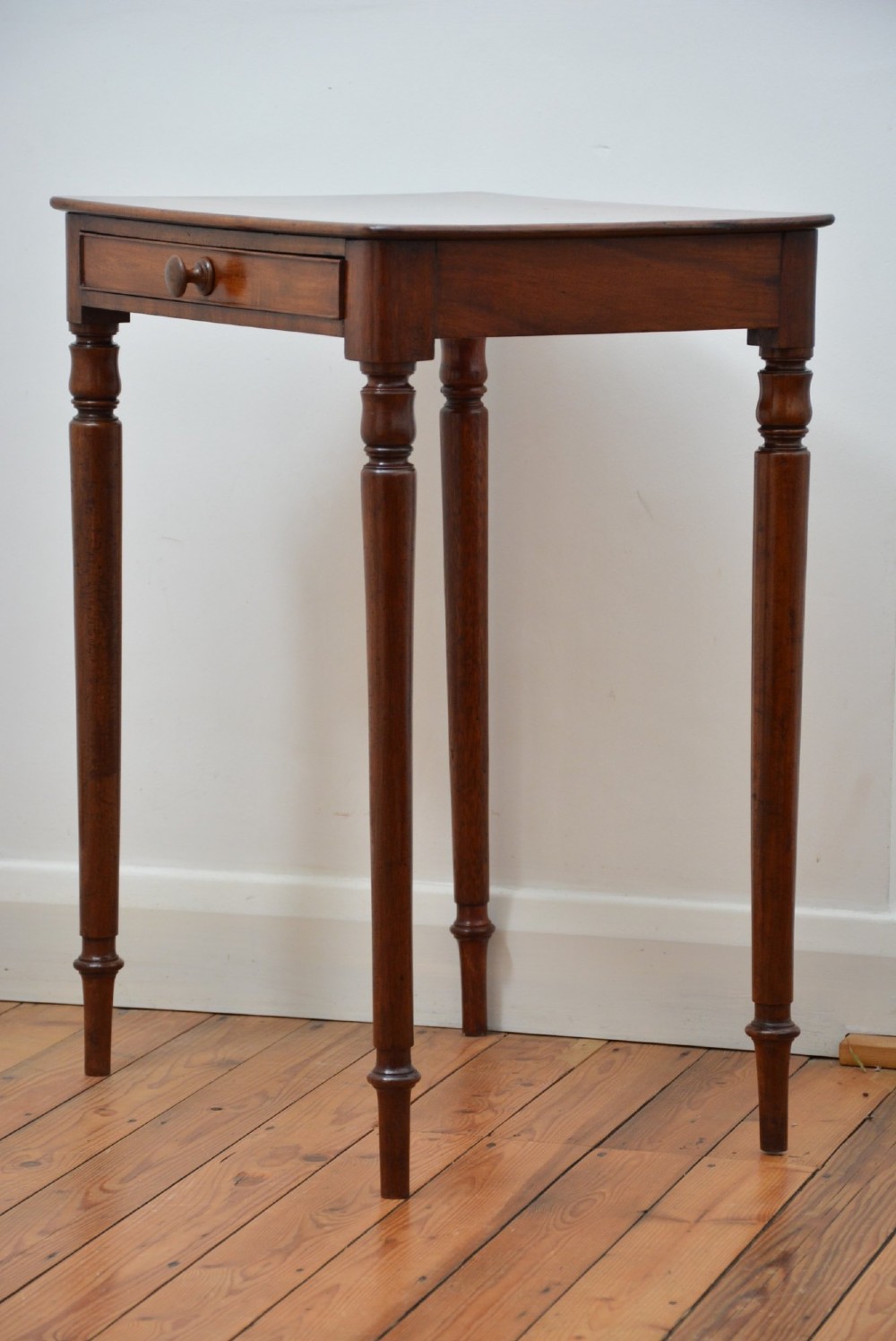 An English William IV mahogany side table featuring a single frieze drawer with a turned wooden knob handle and slim turned legs. View II