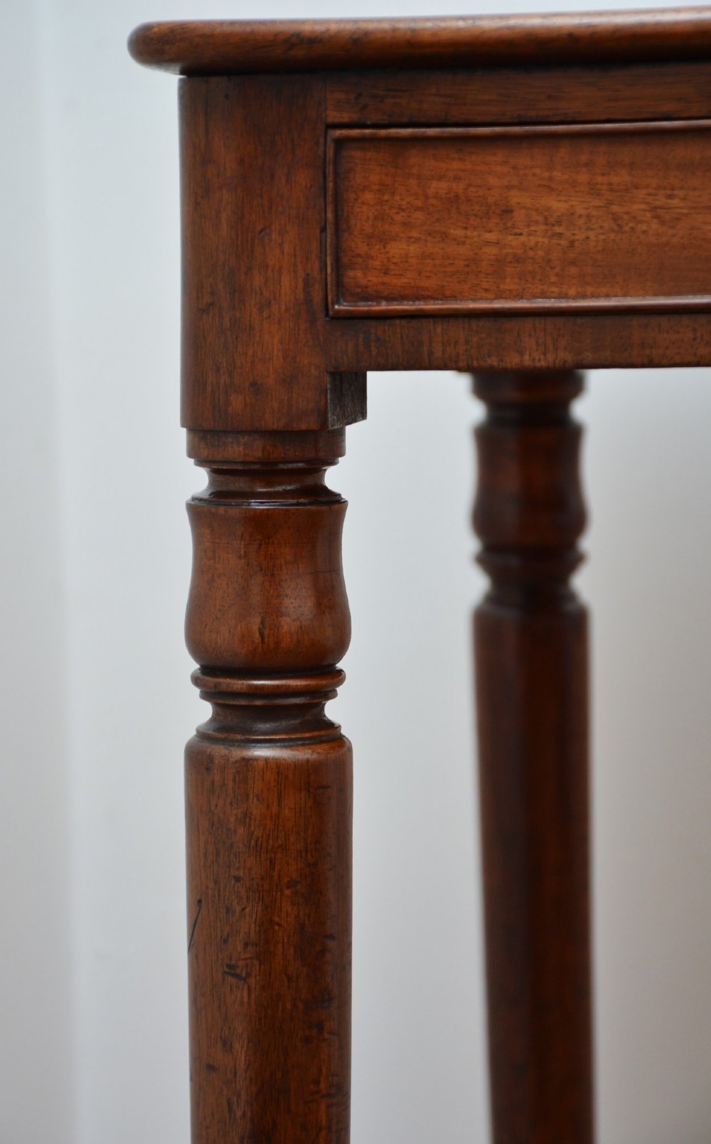 An English William IV mahogany side table featuring a single frieze drawer with a turned wooden knob handle and slim turned legs. View IX