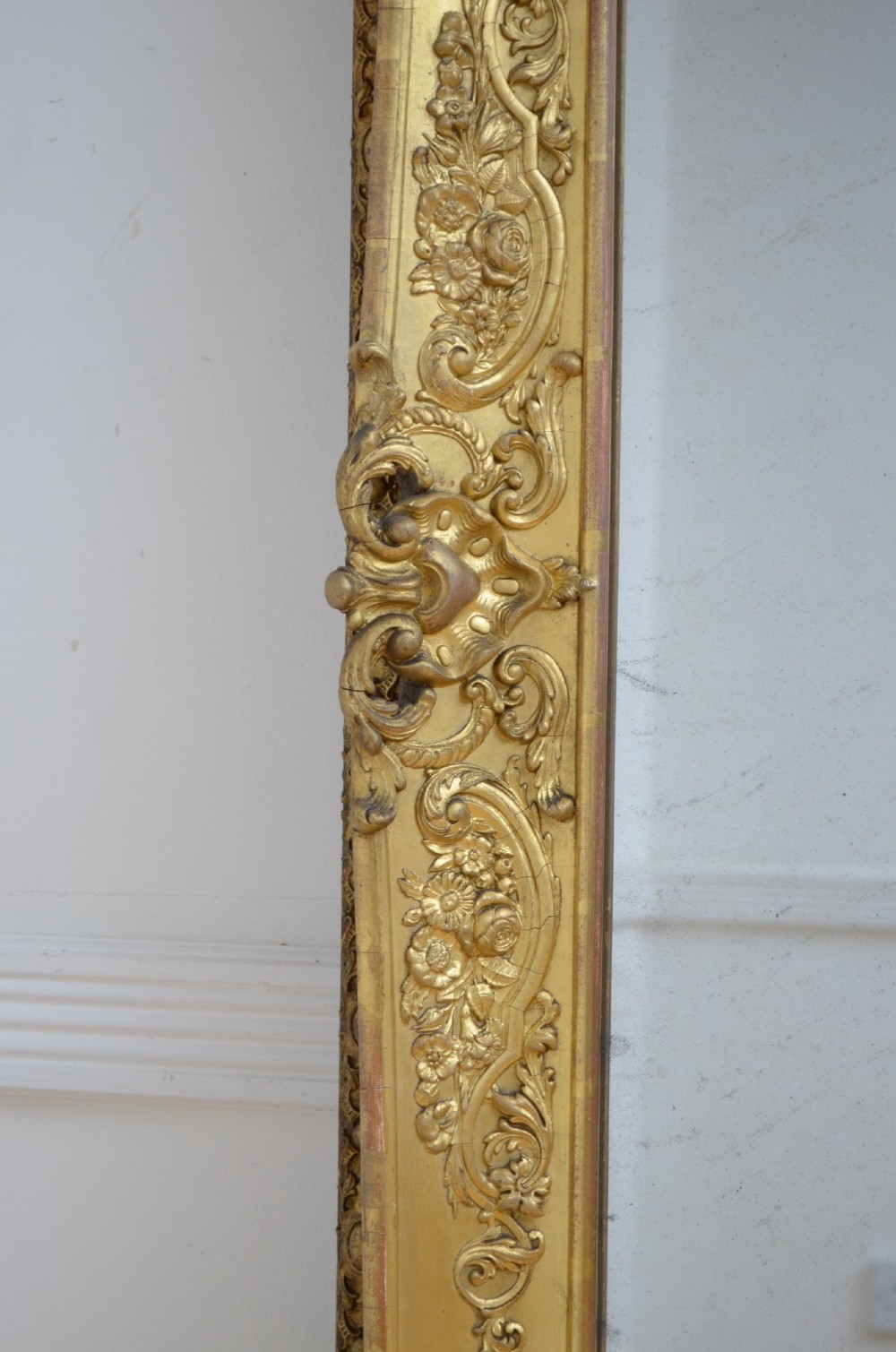 A tall rectangular floor-standing mirror with a gold-leaf gilded frame featuring intricate gesso moulding along the borders and corners. View VIII