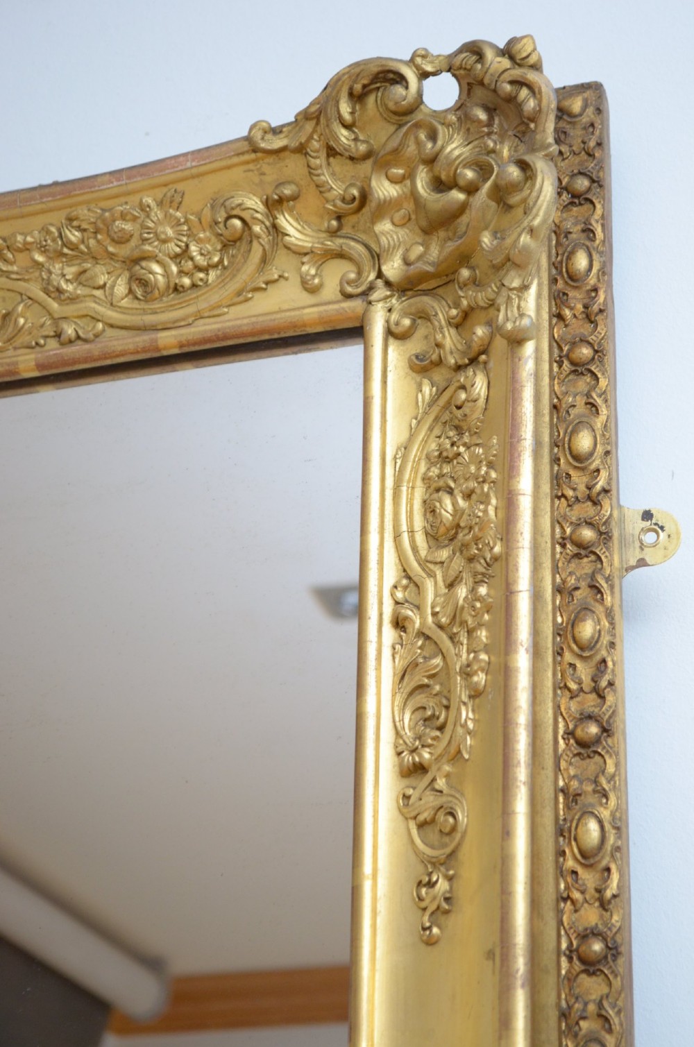 A tall rectangular floor-standing mirror with a gold-leaf gilded frame featuring intricate gesso moulding along the borders and corners. View XII