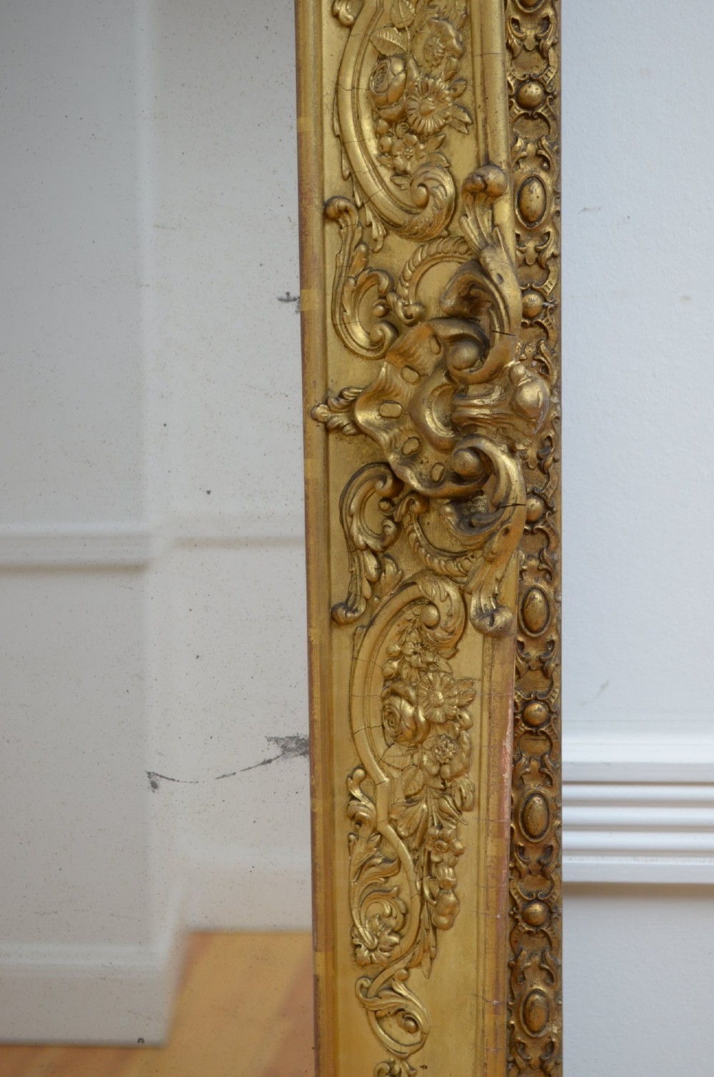 A tall rectangular floor-standing mirror with a gold-leaf gilded frame featuring intricate gesso moulding along the borders and corners. View XIV