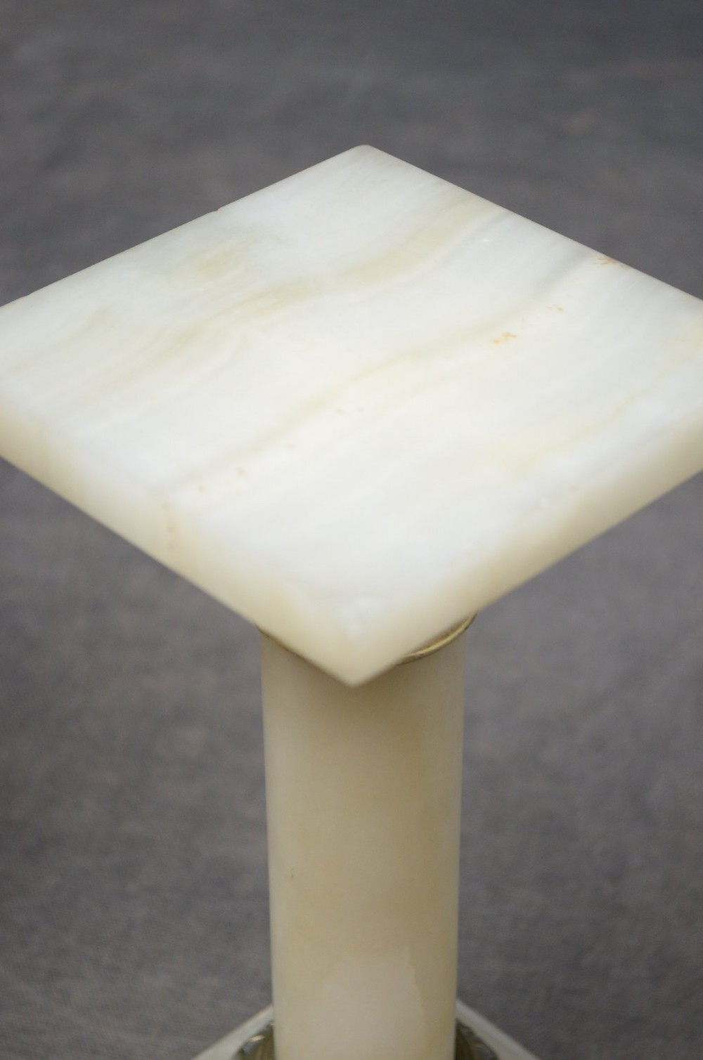 A pair of low Neoclassical onyx pedestal columns with square stepped bases, cylindrical stone shafts, and decorative brass capitals. View VII