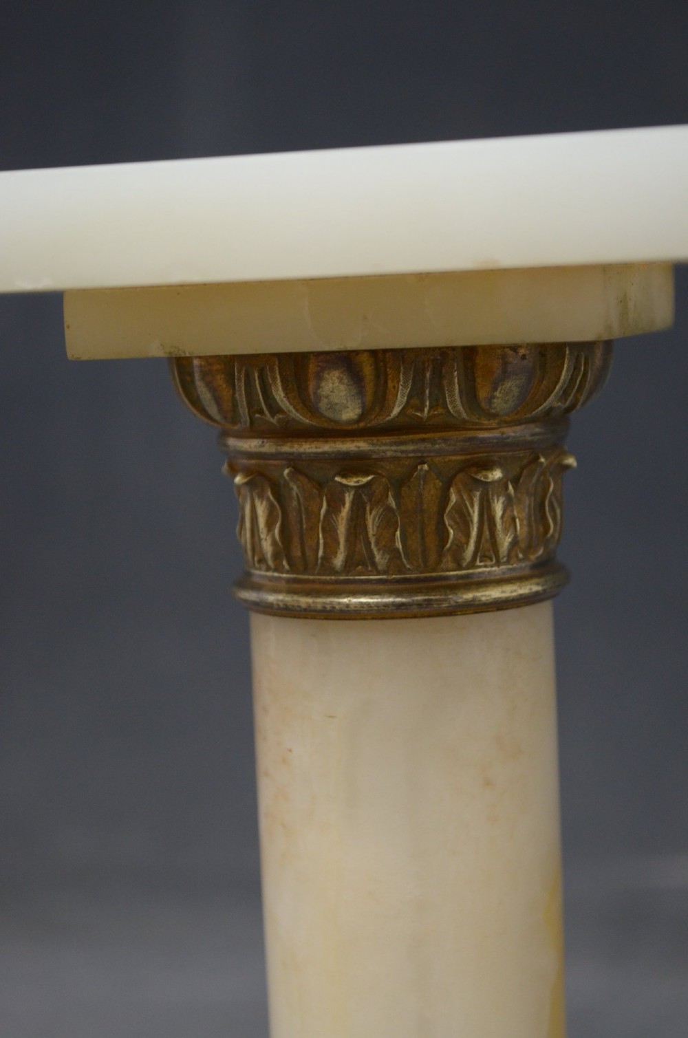 A pair of low Neoclassical onyx pedestal columns with square stepped bases, cylindrical stone shafts, and decorative brass capitals. View X