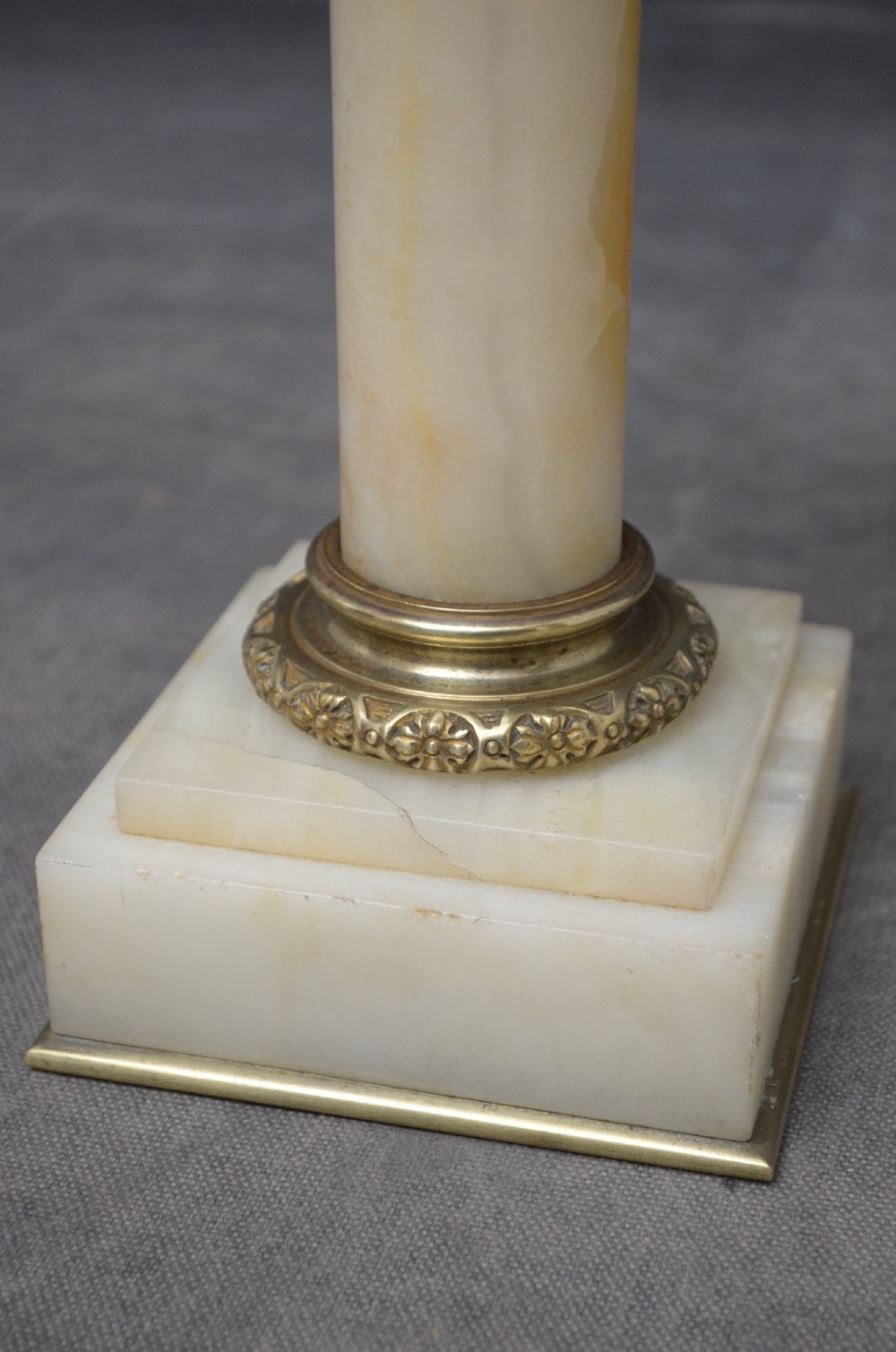 A pair of low Neoclassical onyx pedestal columns with square stepped bases, cylindrical stone shafts, and decorative brass capitals. View XI