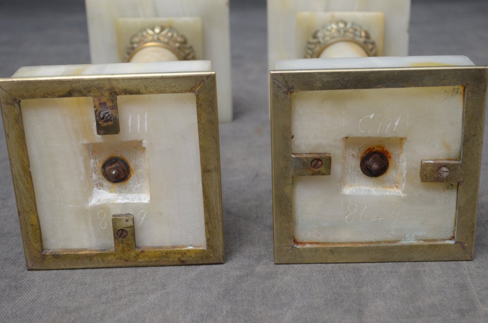 A pair of low Neoclassical onyx pedestal columns with square stepped bases, cylindrical stone shafts, and decorative brass capitals. View XIII