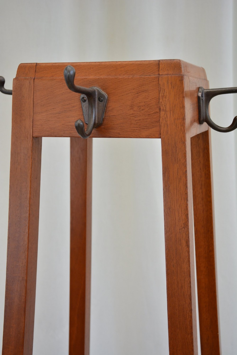 A tall, square-framed Art Deco wooden coat stand with dark metal hanging hooks and a lower umbrella drip tray. View VIII