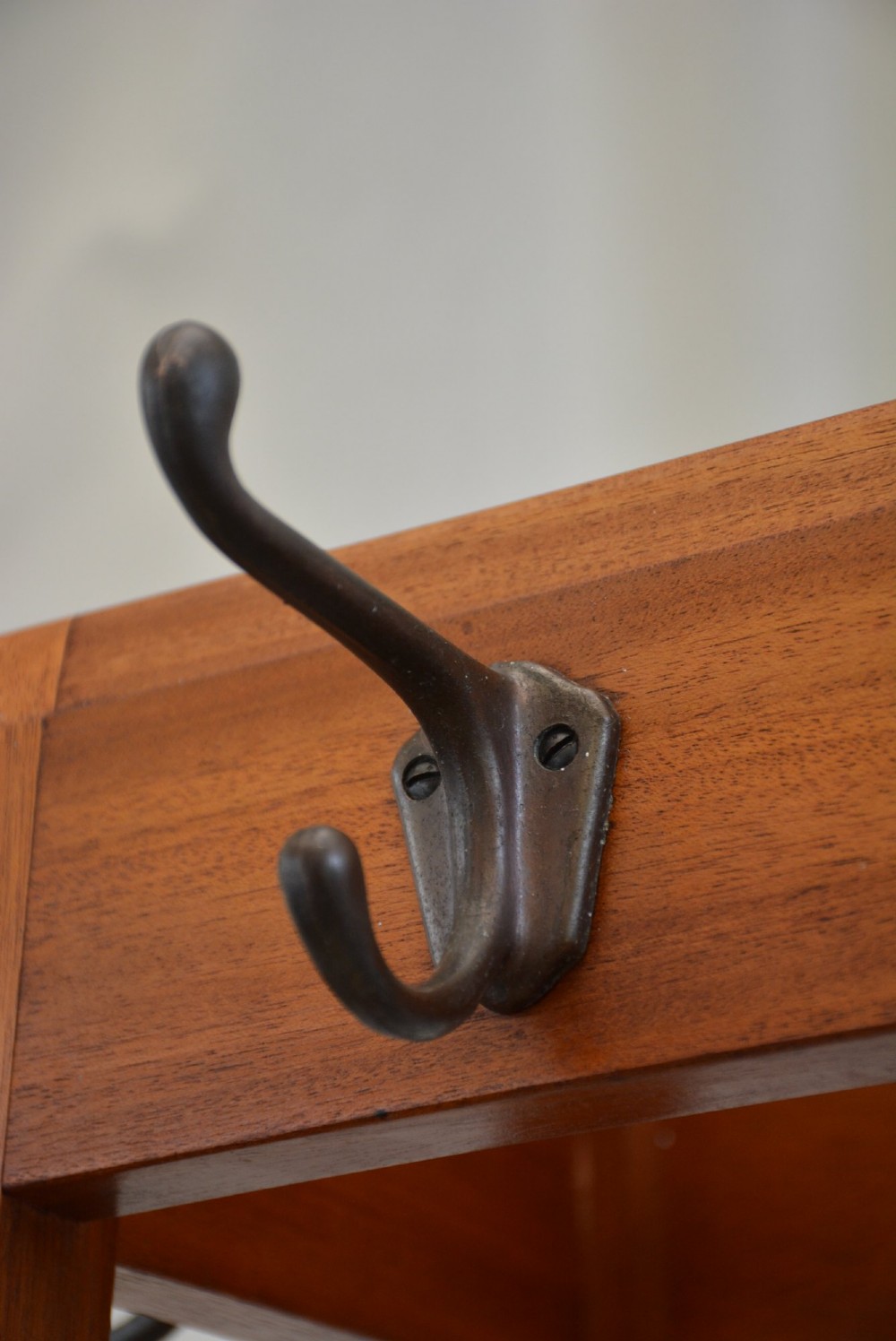 A tall, square-framed Art Deco wooden coat stand with dark metal hanging hooks and a lower umbrella drip tray. View X