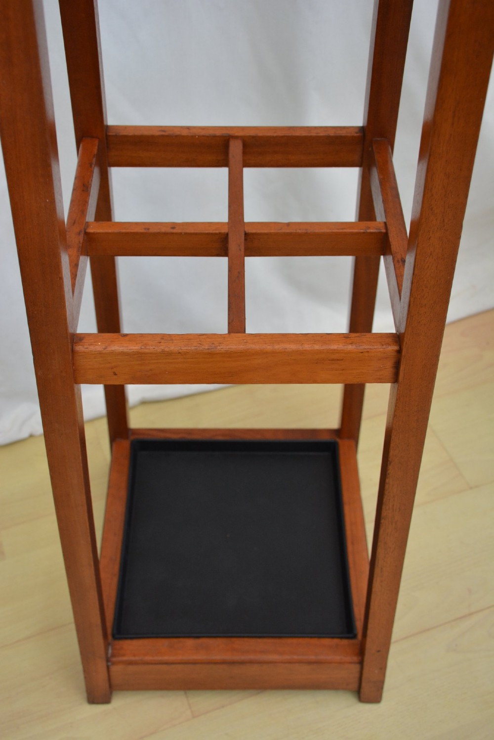 A tall, square-framed Art Deco wooden coat stand with dark metal hanging hooks and a lower umbrella drip tray. View XII
