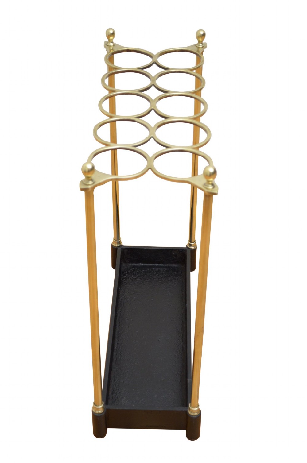 A Victorian brass umbrella stand featuring an eight-ring top frame, four tubular posts with ball finials, and a rectangular black cast iron drip tray. View V