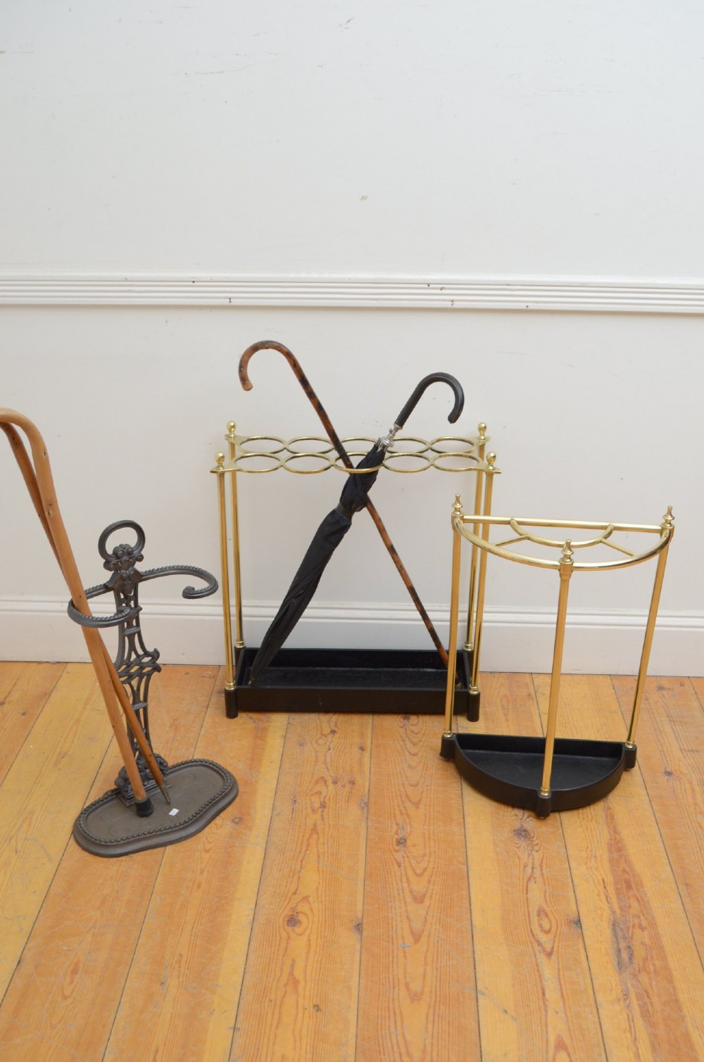 A Victorian brass umbrella stand featuring an eight-ring top frame, four tubular posts with ball finials, and a rectangular black cast iron drip tray. View VII