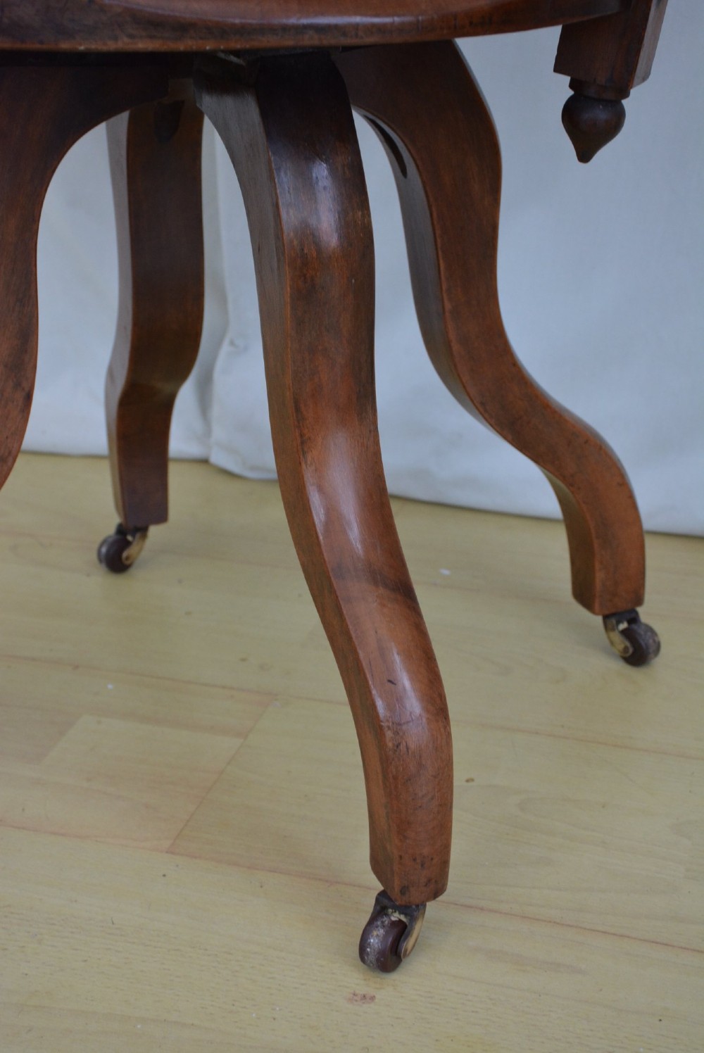 An antique walnut revolving desk chair featuring a curved horseshoe backrest with turned spindles, a circular wooden seat, and four splayed legs on castors. View VII