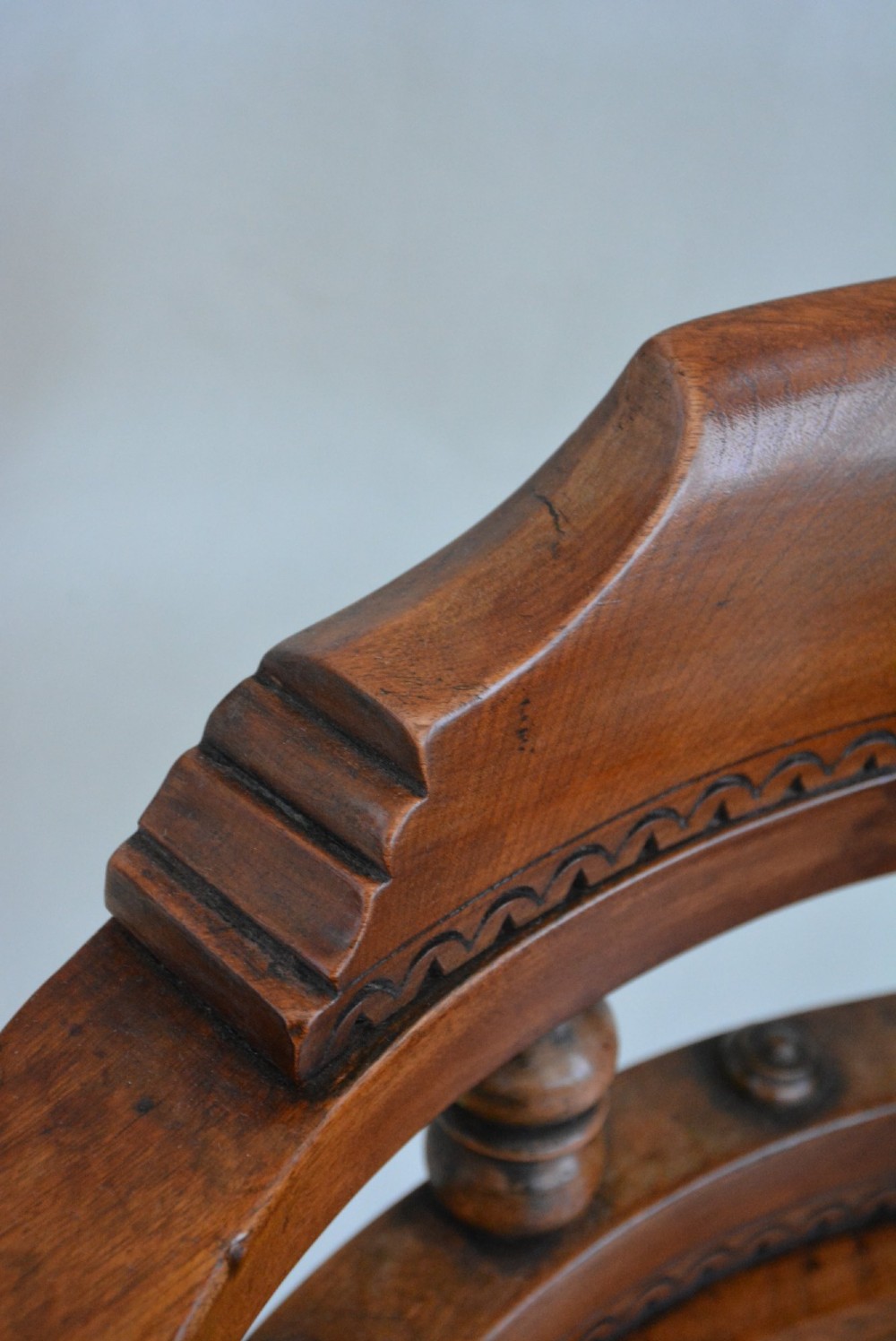An antique walnut revolving desk chair featuring a curved horseshoe backrest with turned spindles, a circular wooden seat, and four splayed legs on castors. View IX