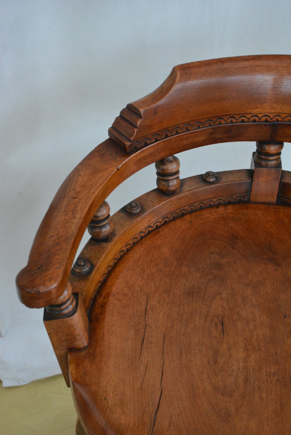 An antique walnut revolving desk chair featuring a curved horseshoe backrest with turned spindles, a circular wooden seat, and four splayed legs on castors. View XII