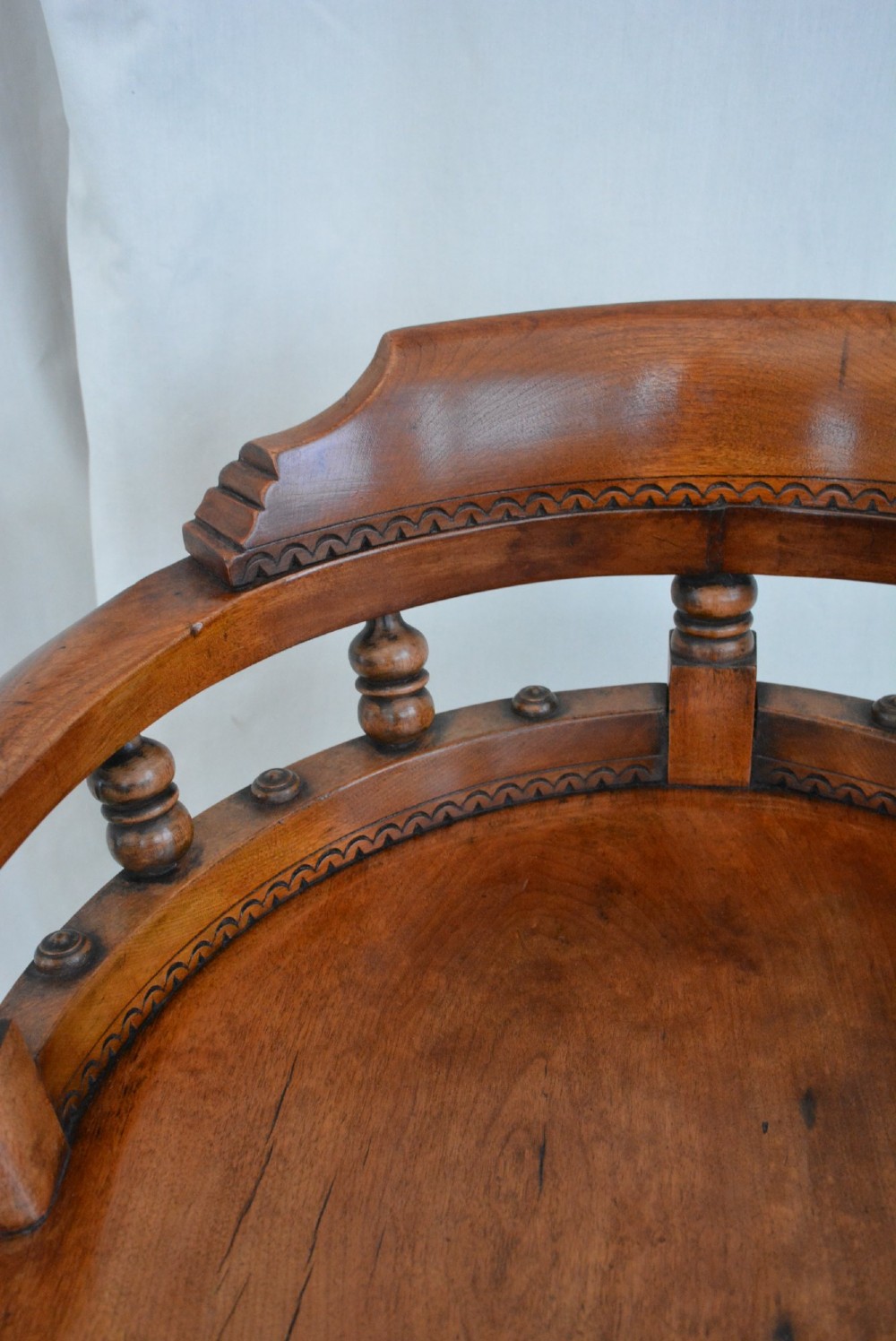 An antique walnut revolving desk chair featuring a curved horseshoe backrest with turned spindles, a circular wooden seat, and four splayed legs on castors. View XIII