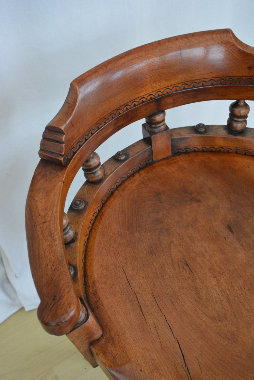 An antique walnut revolving desk chair featuring a curved horseshoe backrest with turned spindles, a circular wooden seat, and four splayed legs on castors. View XIV