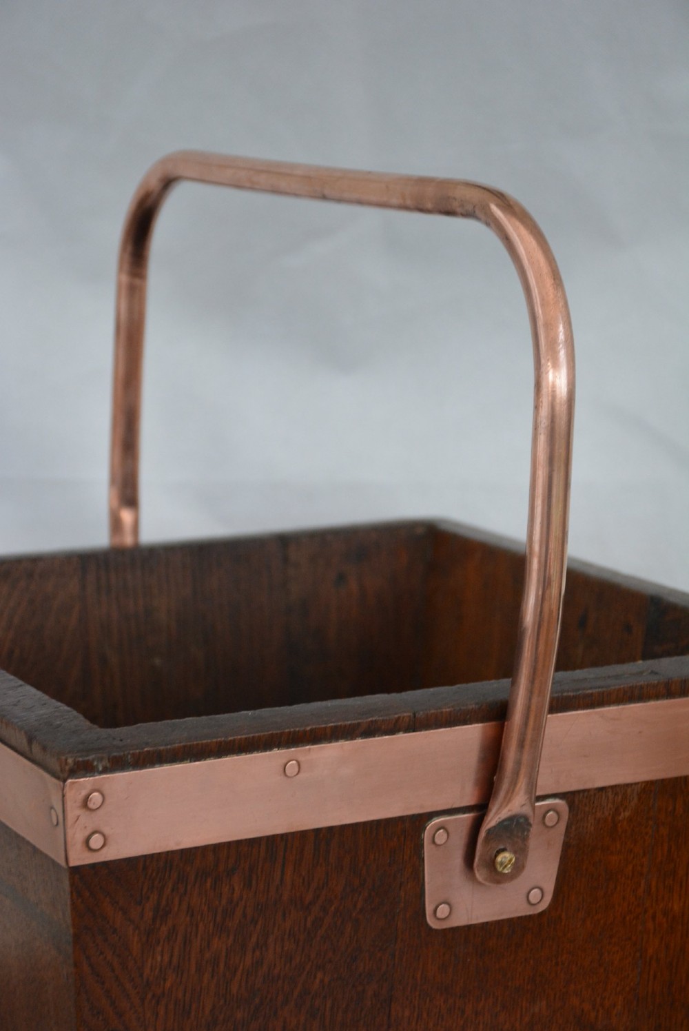 A tapered dark oak wooden coal bucket bound with copper straps and featuring a copper swing handle. View V