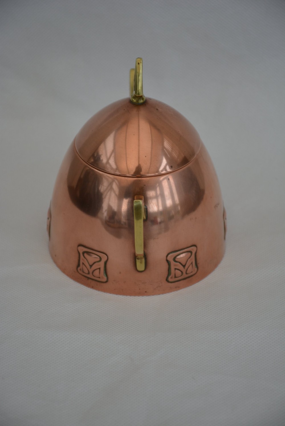 An Art Nouveau copper sugar bowl featuring angular brass handles, a conical lid with a stylised finial, and embossed geometric motifs around the base. View IV