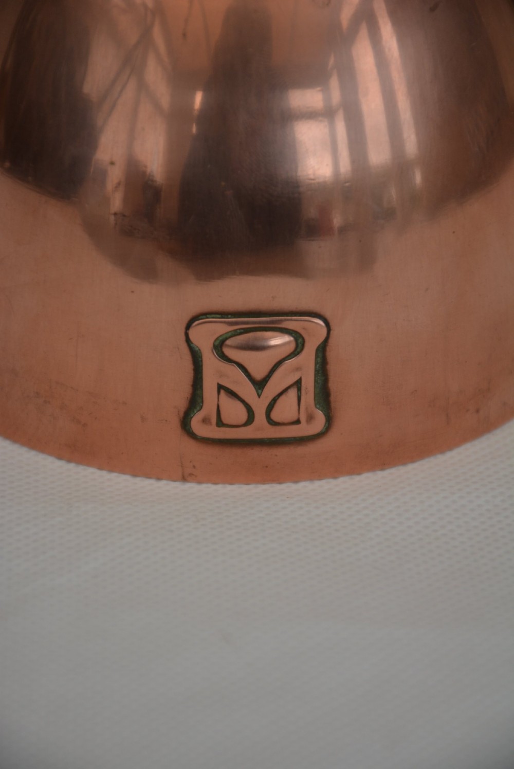 An Art Nouveau copper sugar bowl featuring angular brass handles, a conical lid with a stylised finial, and embossed geometric motifs around the base. View X