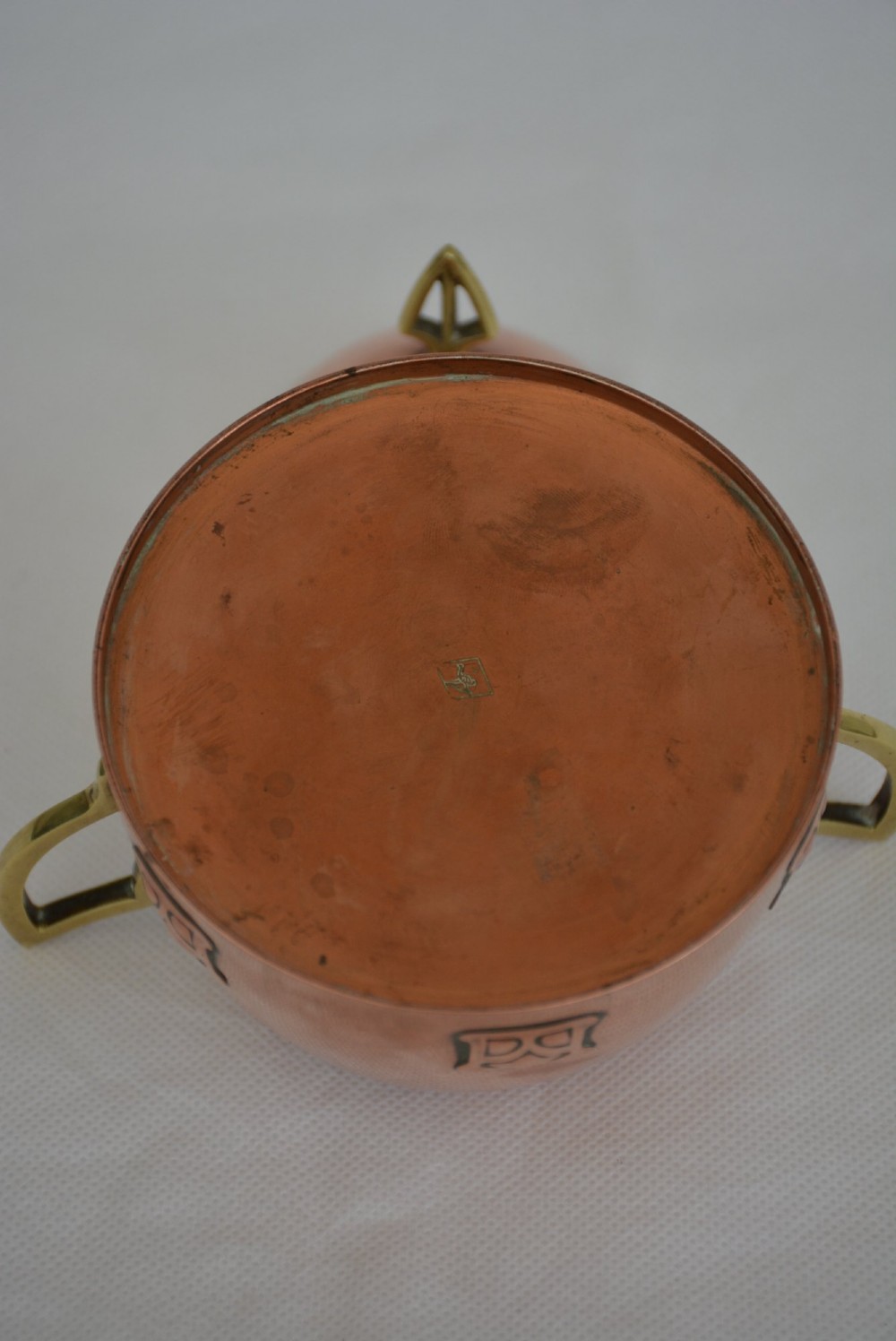 An Art Nouveau copper sugar bowl featuring angular brass handles, a conical lid with a stylised finial, and embossed geometric motifs around the base. View XII